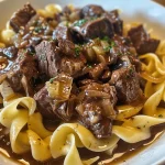 Close-up shot of tender beef tips served with wide egg noodles.