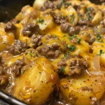 Close-up of a cheesy one pot beef and potatoes dish with melted cheese on top.