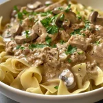 Close-up view of a creamy turkey stroganoff dish with mushrooms and parsley.