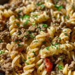 Close-up of a creamy Ground Beef Alfredo dish with pasta and colorful vegetables.