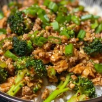A close-up side view of a colorful ground chicken and broccoli stir fry served in a bowl.