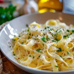 A close-up of creamy garlic tagliatelle pasta with a rich sauce and fresh parsley.