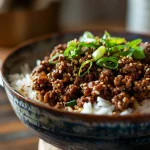 A close-up of a Korean Ground Beef Bowl filled with rice and garnished with green onions and sesame seeds.