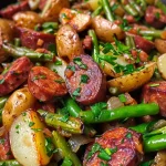 Close-up of sautéed potatoes, green beans, and smoked sausage on a plate.
