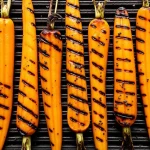 Close-up of grilled baby carrots garnished with fresh mint and lemon zest.