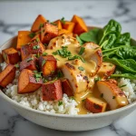 A colorful chicken and sweet potato bowl featuring diced sweet potatoes, sautéed spinach, avocado slices, and lemon wedges.