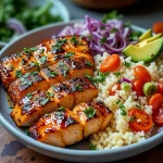 Close-up of a Spicy Honey Sriracha Salmon Bowl featuring vibrant salmon, rice, avocado, and vegetables.