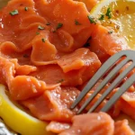 A close-up of Honey Garlic Salmon garnished with lemon slices and parsley, wrapped in foil.