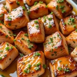 Close-up of honey butter garlic glazed salmon bites garnished with parsley.