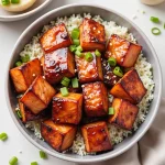 Close-up of Honey Garlic Salmon Bites garnished with green onions and sesame seeds.