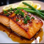 Close-up of crispy honey garlic salmon fillet garnished with green onions and sesame seeds.
