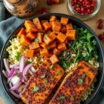Close-up of a Sweet & Spicy Salmon Bowl featuring salmon fillets, roasted sweet potatoes, and sliced avocado in a natural light setting.