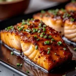 Close-up of crispy honey garlic glazed salmon fillet garnished with green onions.