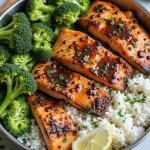 Close-up shot of a Honey Garlic Salmon Meal Prep Bowl with salmon fillets, brown rice, and colorful vegetables.