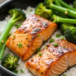 Close-up of honey garlic salmon fillets in an air fryer, with a glossy glaze and garnished with green onions.