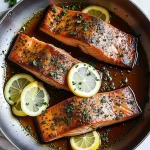 Close-up of honey garlic salmon fillets garnished with green onions, warm lighting highlighting their texture.