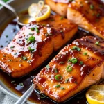Close-up of glazed salmon fillet drizzled with honey garlic sauce, garnished with green onions.
