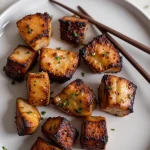 Close-up of golden-brown Air Fryer Honey Garlic Salmon Bites garnished with green onions.