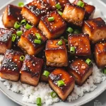 Close-up shot of honey garlic salmon bites garnished with green onions and sesame seeds.