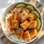 Close-up of golden-brown Honey Garlic Salmon Bites garnished with green onions and sesame seeds.