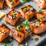 Close-up of Sweet Honey Garlic Salmon Bites garnished with green onions and sesame seeds.