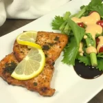 Close-up of Air Fryer Honey Lemon Salmon garnished with lemon wedges.