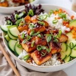 Close-up of honey garlic salmon rice bowls with colorful vegetables and sesame seeds.