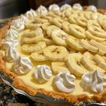 Close-up shot of a sliced banana cream pie with a golden crust.