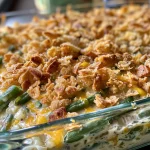A deliciously cheesy green bean casserole with a golden top, viewed from the side.