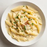A close-up shot of creamy garlic pasta in a single pot, garnished with fresh parsley.