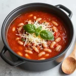 A bowl of Tuscan soup with white beans garnished with fresh herbs.