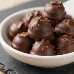Close-up of three ingredient paleo vegan no bake brownie bites arranged on a plate.