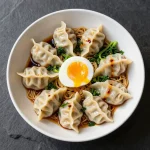 A savory ramen bowl filled with dumplings, soft-boiled eggs, and fresh greens