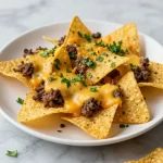 A plate of loaded nachos topped with cheese, jalapenos, and guacamole