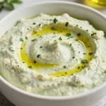 A bowl of lemon and herb white bean dip garnished with fresh herbs and lemon slices