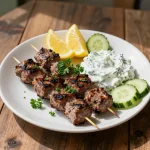 A plate of Mediterranean beef kofta served with fresh herbs and tzatziki sauce